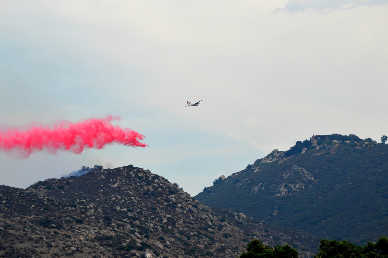 Un avion épand une poudre sur un feu dans les montagnes