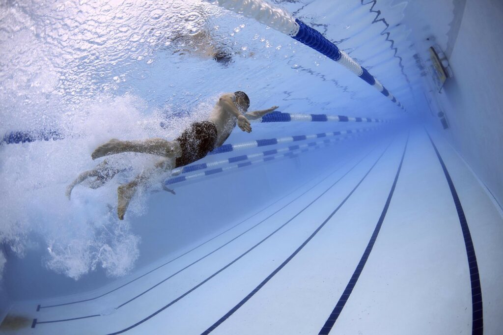 Des nageurs, chacun dans leur couloir de piscine nagent dans une même piscine.