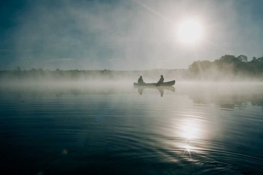 Deux pêcheurs en chaloupe dans le soleil qui se lève: un magnifique loisir en forêt.