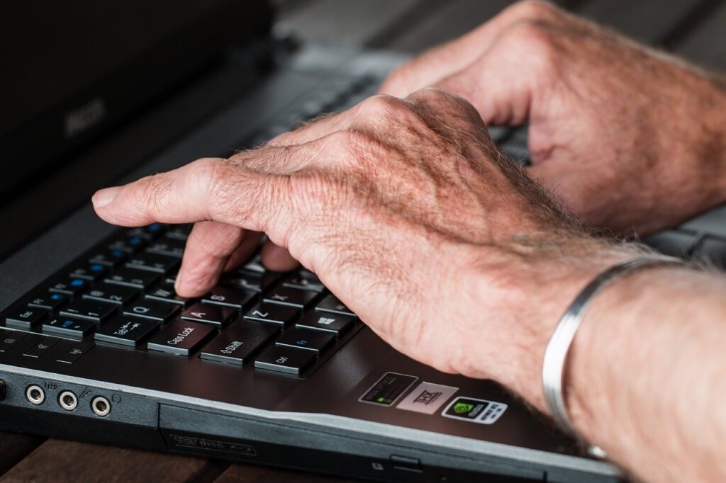 Les mains d'un homme qui tape à l'ordinateur évoquent un gestionnaire en télétravail